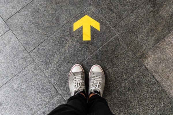 Feet on pavement with an arrow